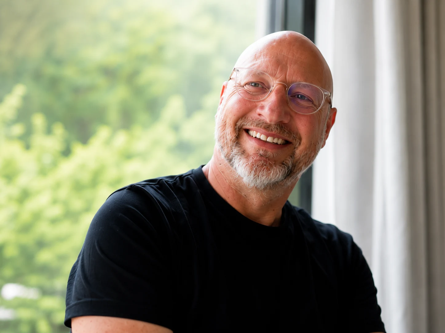 Tom lacht voor een raam met groen