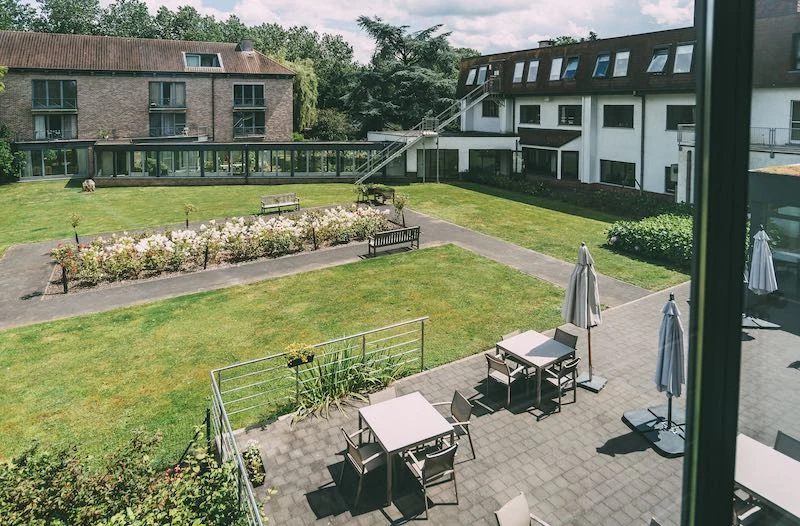 Binnenplaats met gras, bloemperken en terrasmeubels tussen de gebouwen