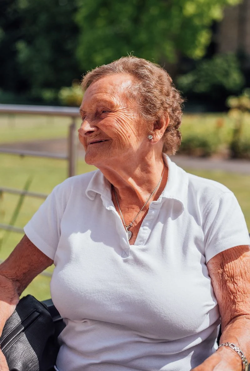 Bewoners en zorgverleners aan een tafel op het terras onder een parasol