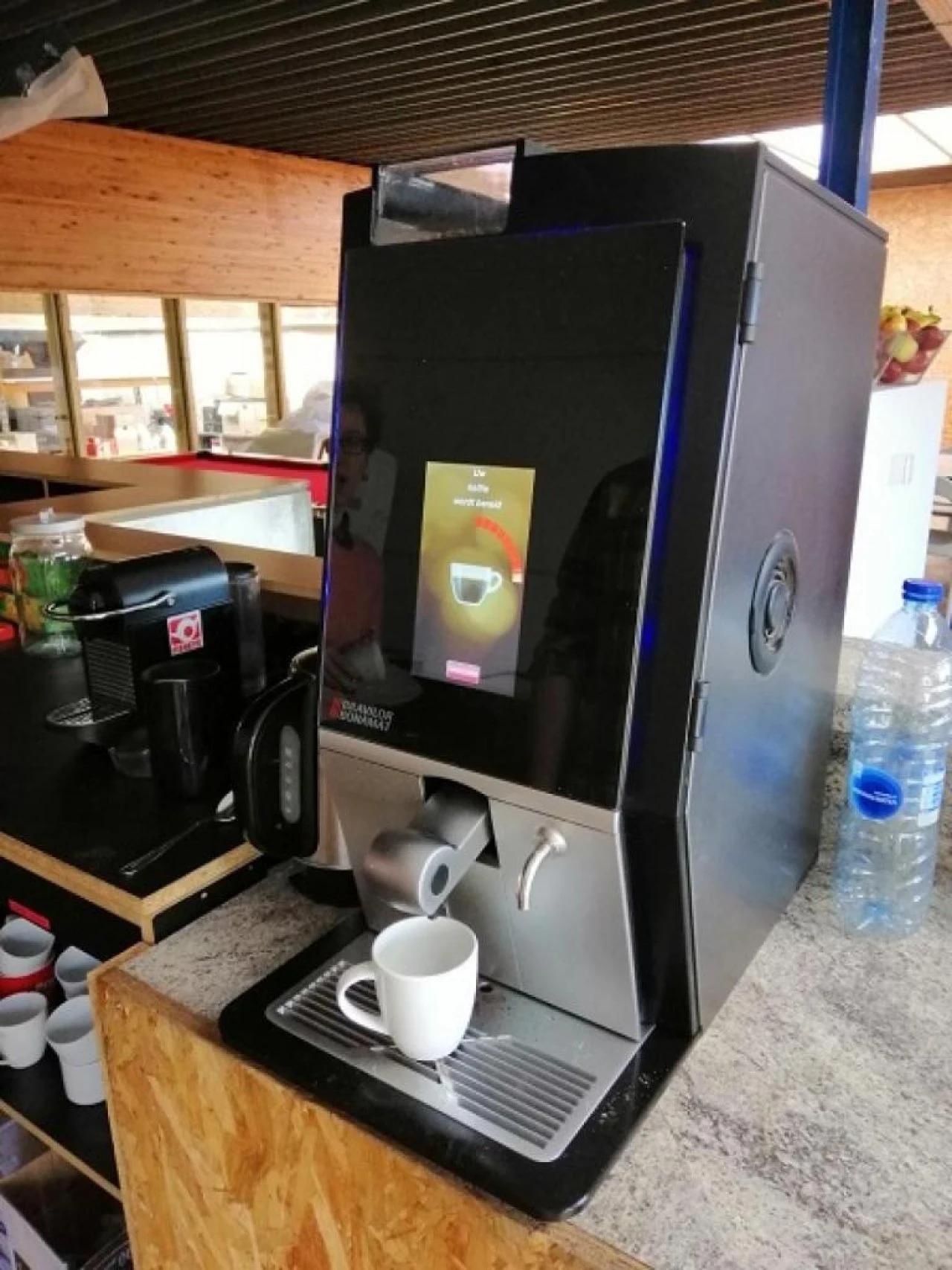 Koffieautomaat met touchscreen en tas onder de uitloop in een bedrijfskeuken