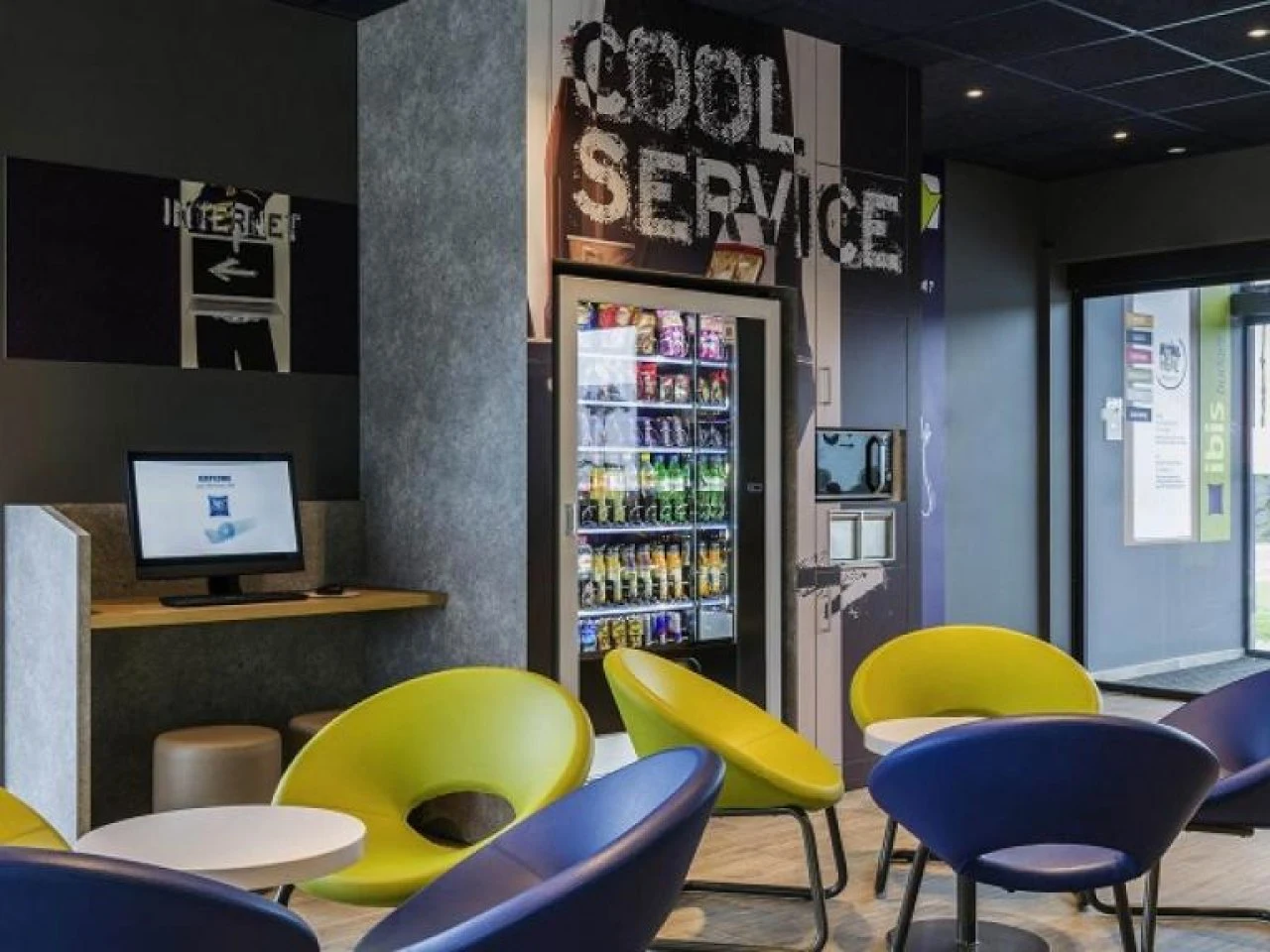 Wachtruimte met gekleurde stoelen en een drank- en snackautomaat naast de balie