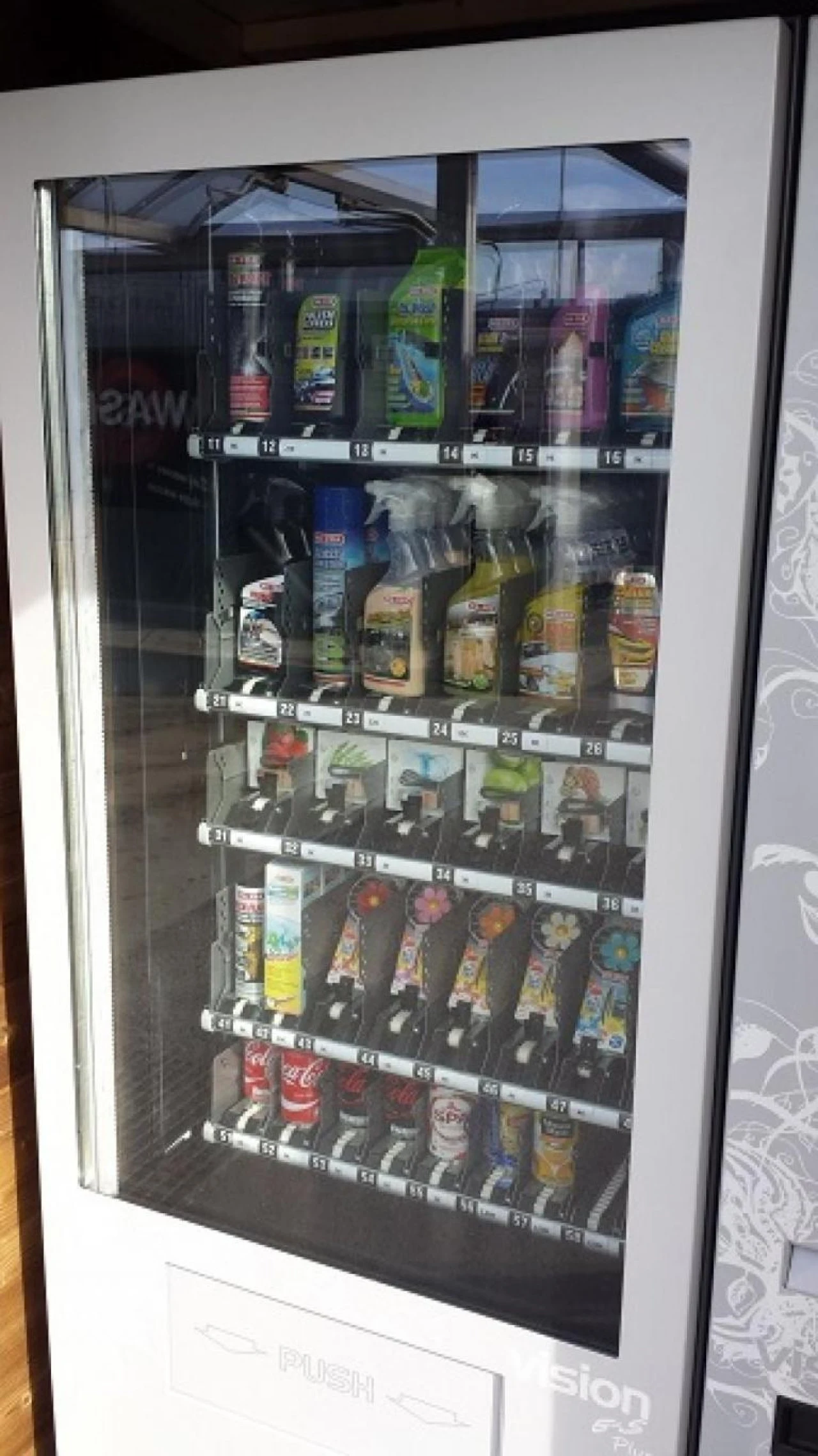 Automaat met onderhoudsproducten, sprays en flessen achter glas bij een carwash