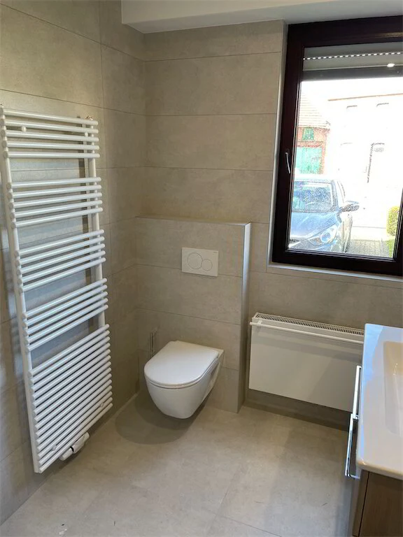 Badkamer met handdoekradiator en hangtoilet