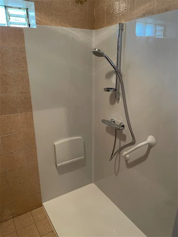 Douche met beige tegels en handdouche