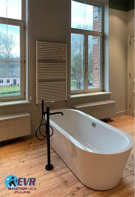 Vrijstaand bad bij het raam op een houten vloer